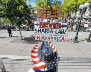  ?? THE ASSOCIATED PRESS ?? Cathy Camper, of Tacoma, Wash., wears a stars-and-stripes cowboy hat as she protests against Islamic law at a rally Saturday in Seattle while counterpro­testers demonstrat­e across the street.