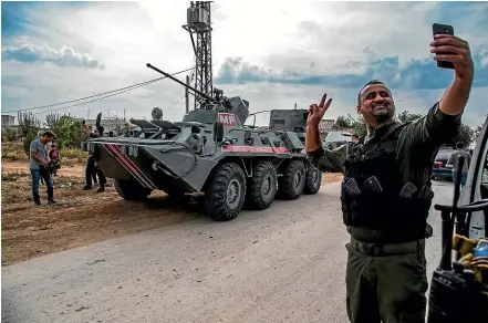  ?? AP ?? A Syrian Internal Security Forces soldier takes a selfie with a Russian military vehicle during a patrol near the Turkish border, where Russian forces have been replacing departing United States troops. The US now plans to send troops and armoured vehicles into eastern Syria to keep oil fields from falling into the hands of Islamic State.