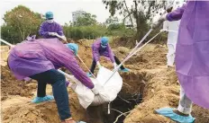  ?? AP ?? ■ People in personal protective suits bury the body of their relative who died of Covid-19 at a cemetery in Delhi.