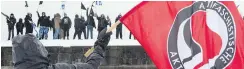  ?? JACQUES BOISSINOT, CP ?? An anti-fascist demonstrat­or waves a flag at members of a right-wing group during competing rallies in Quebec City on Saturday.
