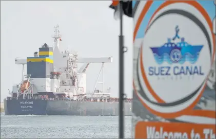  ?? Ayman Aref The Associated Press ?? A cargo ship sails Tuesday past the town of Ismailia, Egypt, as vessel traffic resumed through the Suez Canal.