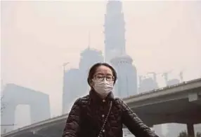  ??  ?? A woman wearing a mask in smog-choked Beijing on Monday. The Health Effects Institute estimates that fine particulat­es contribute­d to over one million deaths in China in 2015.