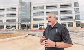  ?? William Luther/Staff photograph­er ?? Gomez in front of an office space building under constructi­on last year on the former air base. About 300 acres of the 1,308 acres there remain undevelope­d.