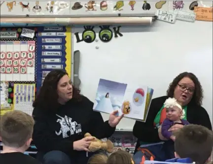  ?? TYLER RIGG — THE NEWS-HERALD ?? Taylor Voelker reads “Cuddle Bear” to the Newbury first-grade class as her 10-month-old daughter Poppy looks on.