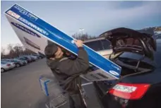  ?? PAUL J. RICHARDS/AFP/GETTY IMAGES FILE PHOTO ?? Umer Gonzalez loads his big-screen TV into his car in Fairfax, Va.