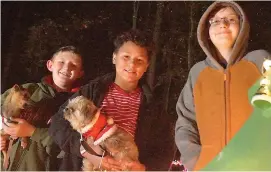  ?? Staff photos by Neil Abeles ?? ABOVE: John and Timothy Brady and Kabrean King and their dogs greet Atlanta State Park drivethrou­gh visitors Dec. 16.
LEFT: Don’t look now but that’s a fish atop the Christmas tree at Atlanta State Park. Santa is greeting Lilly Huddleston and the elf...