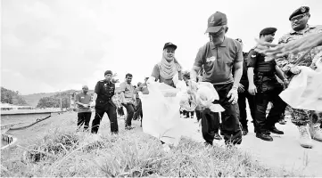  ??  ?? Tengku Abdullah (front) joins the ‘gotong royong’ programme with Lembah Bertam residents during his visit to Cameron Highlands. — Bernama photo