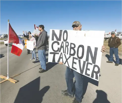  ?? BRENT CALVER / POSTMEDIA NEWS FILES ?? Demonstrat­ors line the Trans-canada Highway west of Calgary protesting the carbon tax increase on Monday. While most households will receive more in rebates than they pay in carbon tax, once you account for the fact
that the tax will slow down the economy, most everyone will be worse off, Carson Jerema says.