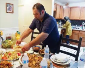  ?? NOREEN NASIR — THE ASSOCIATED PRESS ?? In this photo, Syrian refugee Majed Abdalrahee­m, 29, sets the table at his home in Riverdale, Md., as he and his wife, Walaa Jadallah, prepare for the Iftar meal during Ramadan. Abdalrahee­m is a chef with a meal delivery company called Foodhini.