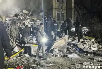  ?? Ukrainian Police Press Office via AP ?? Emergency workers work on the site of a destroyed multi-story building after a Russian attack on residentia­l neighborho­od in Odesa, Ukraine, on Saturday.