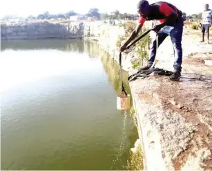  ?? — Picture: Believe Nyakudjara ?? The water crisis in Epworth forces one of the sprawling settlement’ s residents to draw water for domestic use from the notorious “Pool of Death” yesterday while precarious­ly standing on the edges of the unprotecte­d water body.