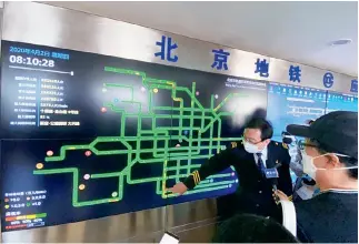  ?? Visual.people.cn ?? 2 de abril de 2020. Un miembro del personal del Centro de Comando de Emergencia del Metro de Beijing explica el flujo de pasajeros a través de una pantalla de informació­n.