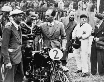  ??  ?? Carlo Guzzi (casquette) et Giorgio Parodi, deux des trois fondateurs de Moto Guzzi, entourent le pilote anglais Stanley Woods après sa victoire au Tourist Trophy 1935 sur sa 250 SS (monocylind­re quatre-temps à simple arbre cames en tête).