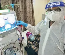  ??  ?? A staff member of The Kidney Hub attending to a patient on dialysis treatment with full personal protective equipment.