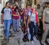  ?? — PTI ?? DCW chairperso­n Swati Maliwal ( left) and the police escort the Nepali girls after they were rescued from Munirka area of New Delhi early on Wednesday.