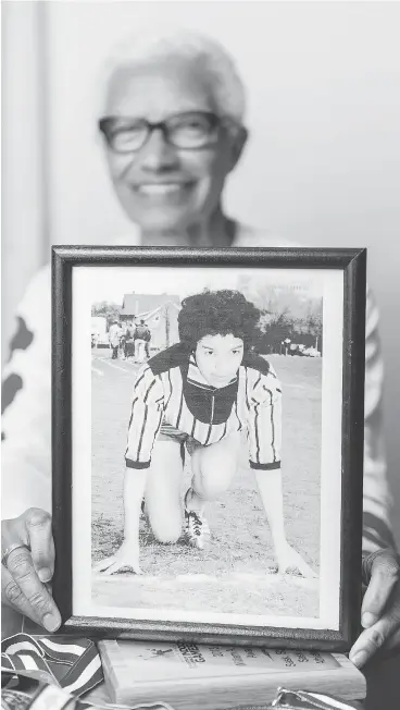  ?? QC PHOTO BY MICHAEL BELL ?? Carol LaFayette-Boyd holds a photo of herself from a high school track event.