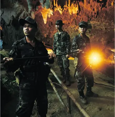 ?? LILLIAN SUWANRUMPH­A / AFP / GETTY IMAGES ?? Thai soldiers relay electric cable deep into the Tham Luang cave in Thailand’s Chiang Rai province in a bid to rescue a group trapped after heavy monsoon rains.