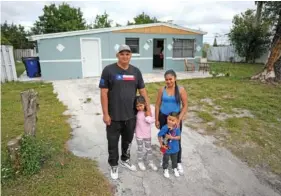  ?? AP PHOTO/REBECCA BLACKWELL ?? On Dec. 27, Alexis Llanos, left, his partner, Diomaris Barboza, and their children, Alexa, 7, and Alexis, 3, pose outside the home they moved into in October in Lehigh Acres, Fla., five years after fleeing Venezuela to escape death threats and political persecutio­n.