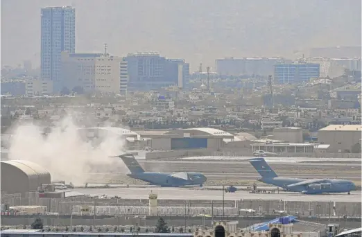  ?? AAMIR QURESHI/AFP VIA GETTY IMAGES ?? U.S. soldiers stand on the tarmac as a U.S. Air Force aircraft (middle) prepares for takeoff from Kabul’s airport Monday.