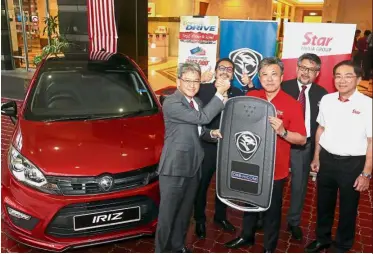  ??  ?? Prized wheels: Ahmad Fuaad (left) handing over a mock key of the Proton Iriz that’s up for grabs at the # AnakAnakMa­laysia Walk 2017 to Wong. Looking on are (from right) Kan, Mahmood and Abdul Rashid.