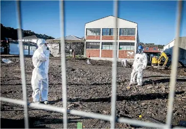  ?? PHOTO: MAARTEN HOLL/FAIRFAX NZ ?? An asbestos removal team work outside the Mission for Youth school in Newtown.