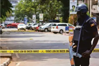  ?? Hajarah Nalwadda / Associated Press ?? Security forces secure the scene of a blast on a street near the parliament­ary building in Kampala, Uganda. At least three civilians died in what police described as a coordinate­d attack.