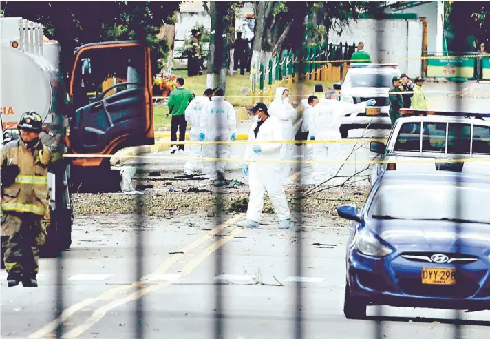  ??  ?? Personal de seguridad en el lugar donde un autobomba provocó una explosión en la Escuela General Santander de la Policía en Bogotá.
