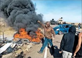  ?? MIKE MCCLEARY/THE BISMARCK (N.D.) TRIBUNE ?? Protesters briefly stand their ground as police and soldiers prepare to move in Thursday.