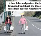  ??  ?? > Ivor John and partner Carly Townsend walk back the three miles from Tesco in Abertiller­y