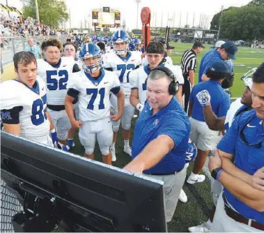  ?? STAFF PHOTO BY MATT HAMILTON ?? McCallie football players and coaches review plays on a sideline monitor during a game at Georgia power Calhoun on Aug. 27. McCallie improved to 3-0 by winning its region opener Friday at Montgomery Bell Academy in Nashville.