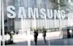  ?? AFP-Yonhap ?? People walk past the Samsung logo displayed on a glass door at the company’s Seocho building in Seoul, April 5.