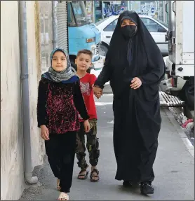  ?? ?? Husseini and her children (AP/Vahid Salemi) walk April 21 in a poor suburb of Tehran.