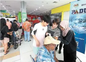  ?? ?? Updating their info: Shoppers stopping by to fill in their personal details at a Padu booth set up at Giant Kota damansara before the Padu registrati­on deadline on March 31. — AZLINA abdullah/the Star
