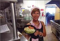  ??  ?? Anna Marie Sepe, of Woonsocket, proprietor of Valentini’s Kitchen in Millrace Kitchen, holds up a prepared dish.