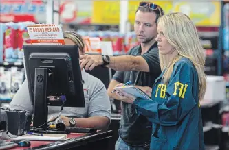  ?? MATIAS J. OCNER TNS ?? An FBI agent speaks with an Autozone employee and jots down informatio­n from the store's computer in Plantation, Fla. Cesar Sayoc, 56, was arrested at the auto parts store on Friday.