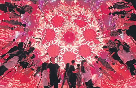  ?? Picture: AP. ?? Visitors watch a light show inside the installati­on Triangle Mirror Video Kaleidosco­pe at a shopping mall in Hong Kong.