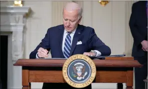  ??  ?? The Associated Press
President Joe Biden signs an executive order on climate change, in the State Dining Room of the White House, Wednesday.