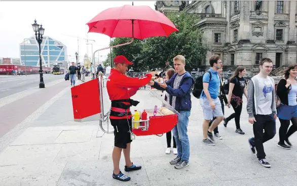  ?? RICK STEVES ?? Sampling one of Germany’s hundreds of sausage varieties from a portable human hotdog stand is a classic German experience.