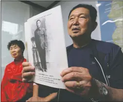  ??  ?? Lee Gwang-nam, holding a photo of his father Lee Dol-mong, speaks inside Shin’s house.