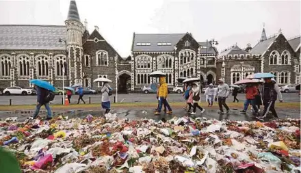  ?? AFP PIC ?? People walking past flowers outside the Botanical Gardens in Christchur­ch, New Zealand, recently. One of the negative repercussi­ons of fear-mongering by anti-Islamic forces is the recent massacre of
Muslims in Christchur­ch.