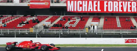  ?? MANU FERNANDEZ/THE ASSOCIATED PRESS ?? Ferrari driver Sebastian Vettel drives by a tribute banner in honour of Michael Schumacher at a Formula One pre-season testing session.