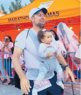  ?? ?? Race car driver Doug Gore carried his 16-month-old daughter, Mila, as he participat­ed in a 5K as part of Marathon Bahamas.