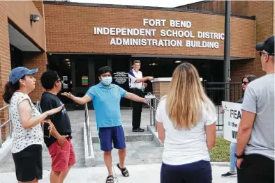  ?? Karen Warren / Staff photograph­er ?? Abhi Gajja, center, explains why he will call for the Fort Bend ISD Board of Trustees to enact a mask mandate to a small group of parents who don’t want one Wednesday outside the district administra­tion building in Sugar Land.