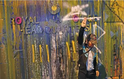  ?? Picture: AFP ?? DEMANDING CHANGE. A pro- democracy protester next to the paint-splattered sign for the police headquarte­rs during an antigovern­ment rally in Bangkok on Wednesday.