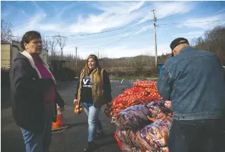  ?? ?? TOP: Danny and Flora Blair wait in their truck for free food from the Hazel Green Food Project in eastern Kentucky. They were first in line after arriving at 4 a.m. ABOVE: Nicky Stacy helps distribute items. Stacy launched the aid effort in February 2021 as a flood response. After Kentucky’s emergency food benefits expired, Stacy said interest in the bimonthly giveaways soared.