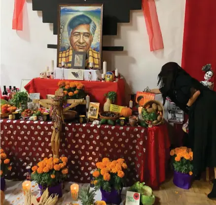  ?? RECORDER FILE PHOTO BY ESTHER AVILA ?? Claudia de la Rosa lights a candle for activist Cesar Chavez’s altar at the 2021 Dia de los Muertos at the Comision Honorifica Mexicana Americana Community Center. The event that honors and remembers departed loved ones each year will be held on November 2.