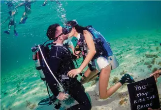  ?? Courtesy Tania Nacif/New York Times ?? Alex Miethe and Ariel Slusher-Miethe kiss during their underwater scuba diving wedding ceremony in Cozumel, Mexico. Some couples are going to great lengths to have an adventure wedding.