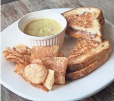  ?? MICHAEL SEARS, MILWAUKEE JOURNAL SENTINEL ?? The Village Cheese Shop grilled cheese sandwich is made with three kinds of cheese. It's served with chips or salad. Also shown, a cup of Wisconsin Soup Co. broccoli cheese soup.