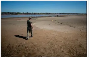  ?? (AP/The Flint Journal, MLive.com/Jake May) ?? Clint Clark of Sanford, Mich., walks Wednesday out into what was once the bottom of Wixom Lake in Edenville Township north of Midland, Mich. A dam failed overnight Tuesday, causing the Tittabawas­ee River to overflow and flood the streets of Midland. More photos at arkansason­line.com/521floodin­g/.