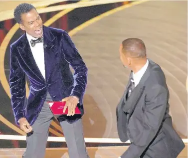  ?? AP ?? Chris Rock (left) reacts after being hit on stage by Will Smith at the Oscars in March.